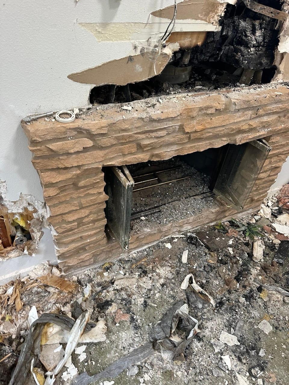A brick fireplace is being demolished in a house.