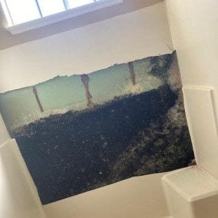 A bathroom with a hole in the wall and a window in Huntington Beach.