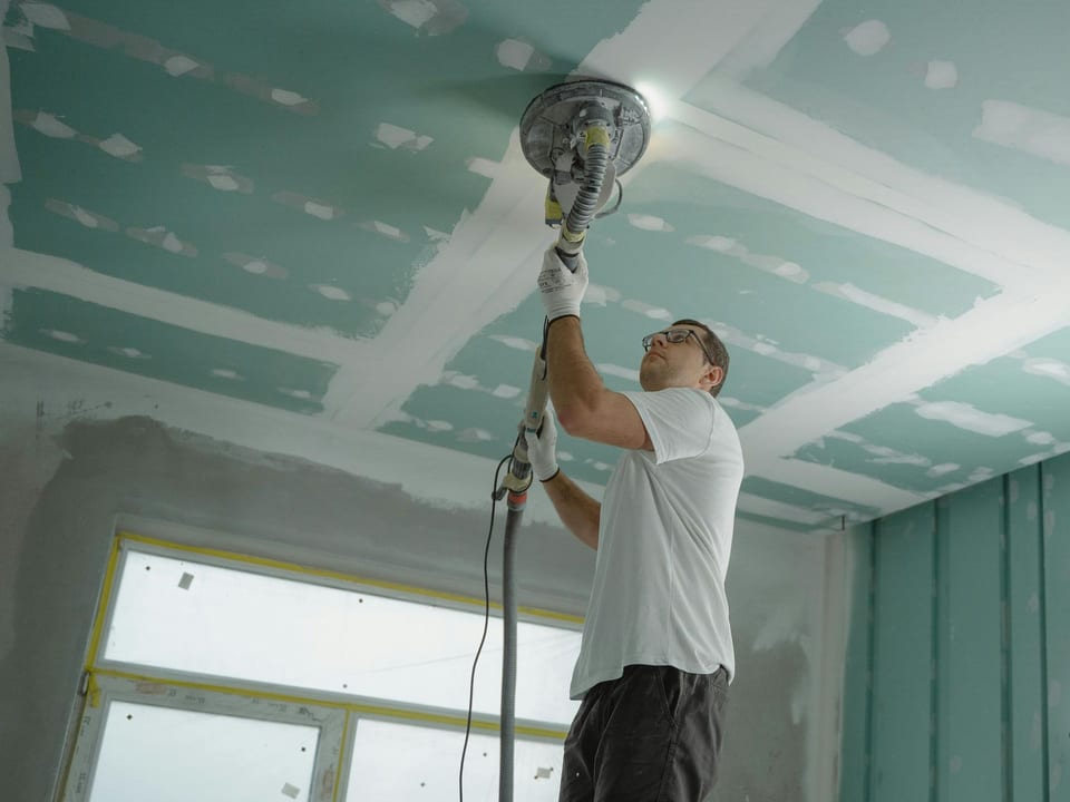 A man is using a sander to sand a ceiling in Santa Ana.