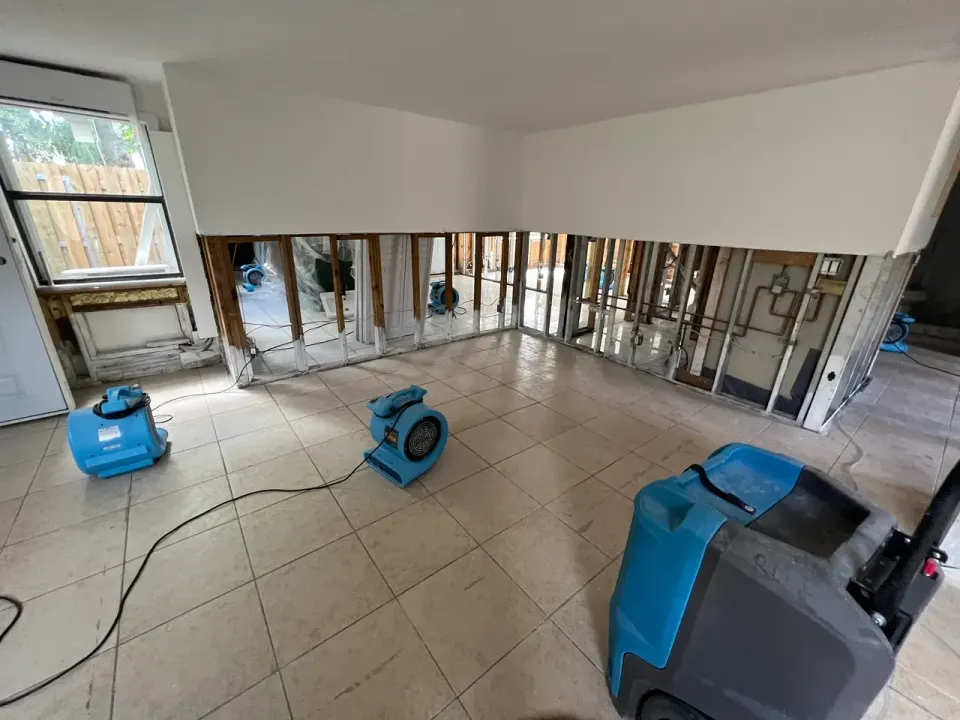 Flood-cut drywall with air movers and a dehumidifier drying a water-damaged room.