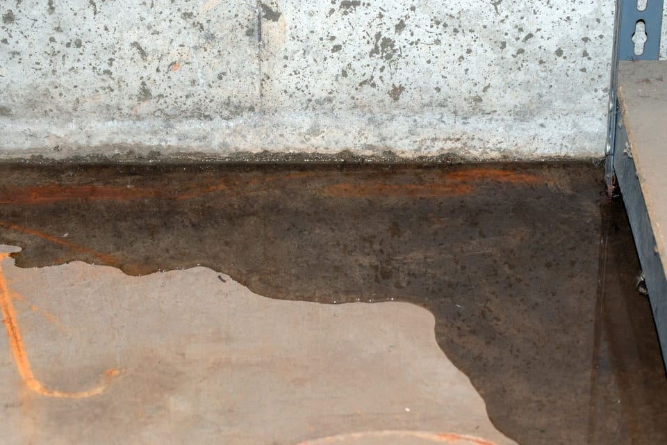 A puddle of water on the ground next to a wall in Orange, CA.